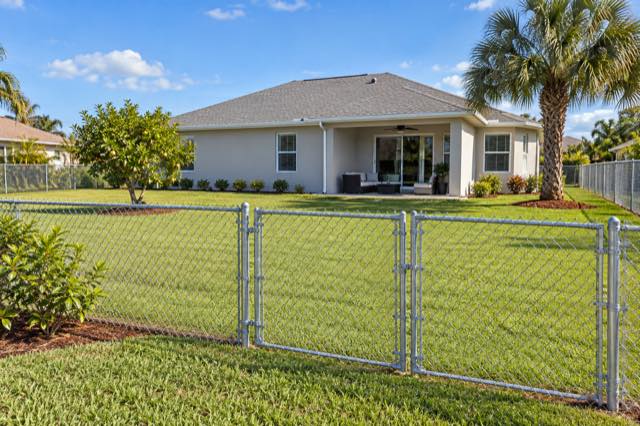 A tidy galvanized chain-link fence around a maintained stucco-home backyard.